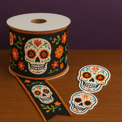 Day of the Dead ribbon spool with sugar skull and floral pattern, alongside colorful sugar skull stickers—perfect accessories for crafts, gifts, and Día de los Muertos decor.