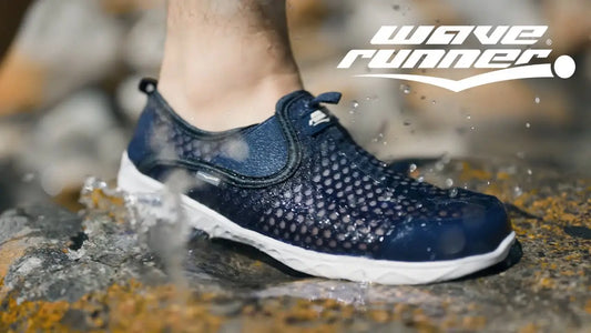 Close-up of a navy blue Wave Runner water shoe on wet rocks, showcasing its breathable mesh design, quick-dry feature, and slip-resistant sole for water activities.