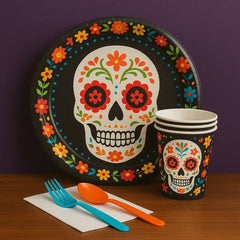 Day of the Dead party supplies with sugar skull plates, matching cups, napkins, and utensils for festive Día de los Muertos celebrations and themed table setups.