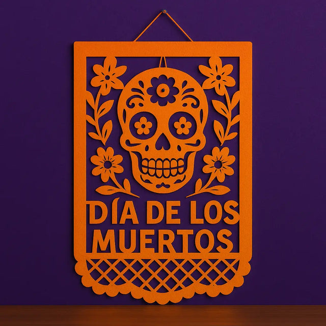 Orange papel picado wall hanging with sugar skull and floral design for Día de los Muertos, perfect Day of the Dead wall decor on purple background.