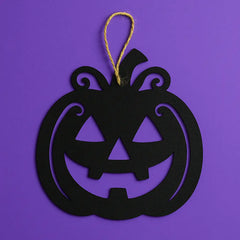 Black jack-o'-lantern wall hanging with swirling vine details, suspended by twine, perfect for Halloween wall or window decorations.