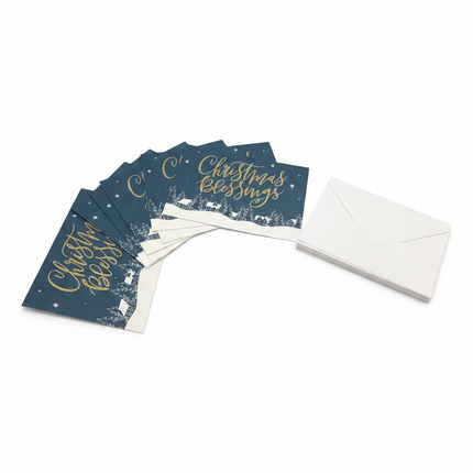 Christmas Blessings cards fanned out showing gold script on navy winter village design with envelopes on white background