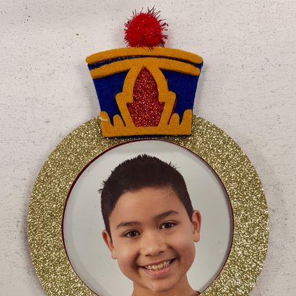 Close up detail of felt nutcracker ornament blue gold military hat and gold glitter photo frame