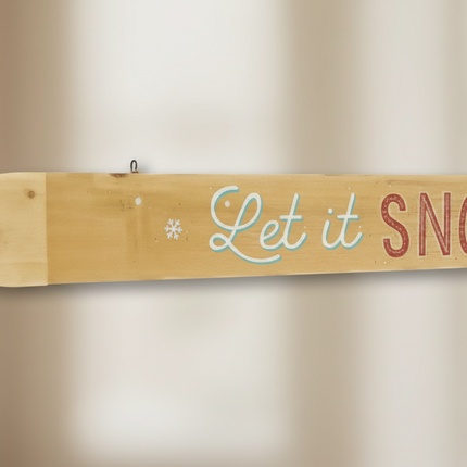 Close-up of rustic wood Let it SNOW wall sign showing wood grain and lettering detail
