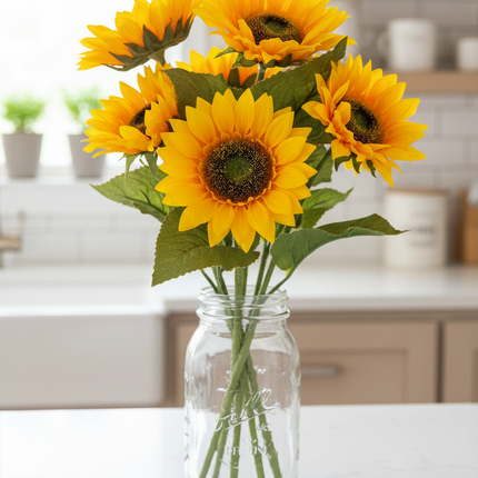 Multiple Ashland dual golden yellow sunflower stems arranged in a large mason jar centerpiece on a bright kitchen counter