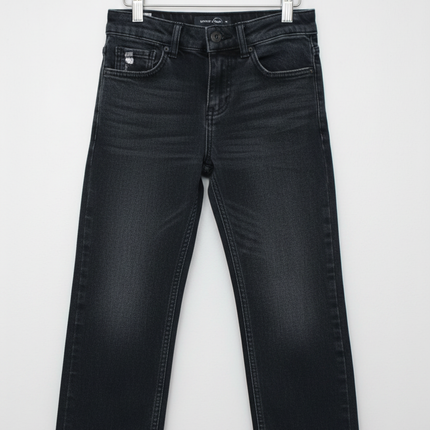 Boys dark wash loose fit skater denim jeans hanging on a white wooden hanger against a white wall