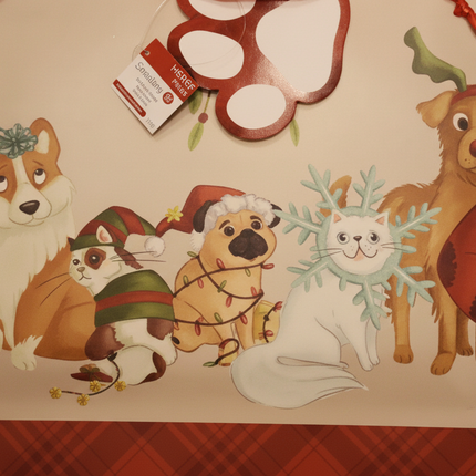 Close up of cute holiday pets design on Christmas gift bag showing corgi pug cat and dog with reindeer antlers in festive outfits