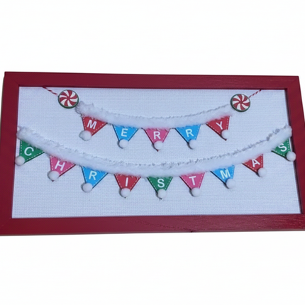 Rectangular wall plaque with red wood frame and colorful Merry Christmas pennant banner with pom-pom garland on white background