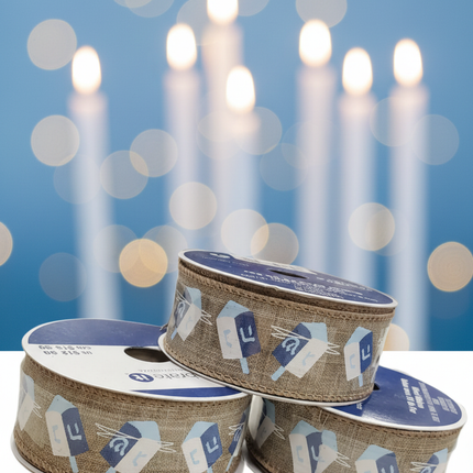 Close up of Celebrate It Hanukkah wired ribbon showing natural burlap texture and blue and white dreidel pattern detail with soft blue bokeh background