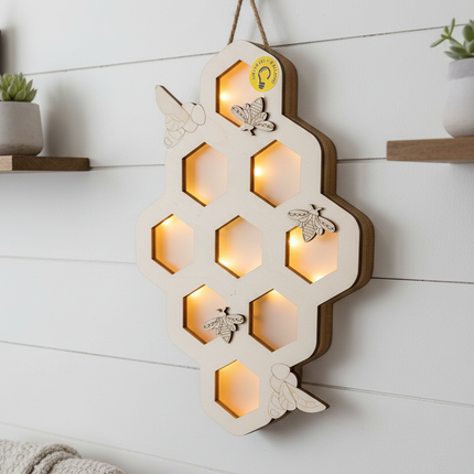 DIY wood honeycomb wall hanging lit up with warm LED lights glowing through hexagons hanging on a farmhouse wall