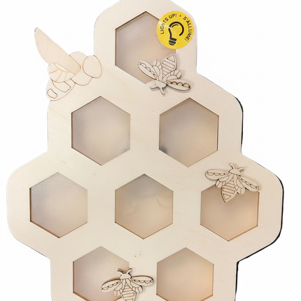 Close-up of DIY wood honeycomb wall hanging showing laser-cut bee detail and hexagon cutout texture with rope hanger