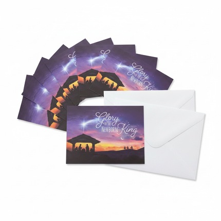 Glory to the Newborn King Christmas cards fanned out showing Nativity silhouette design with envelopes on white background