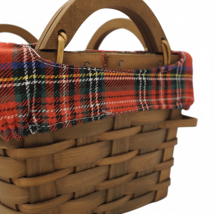 Close-up of woven wicker basket weave texture with small side handle and red tartan plaid fabric liner detail