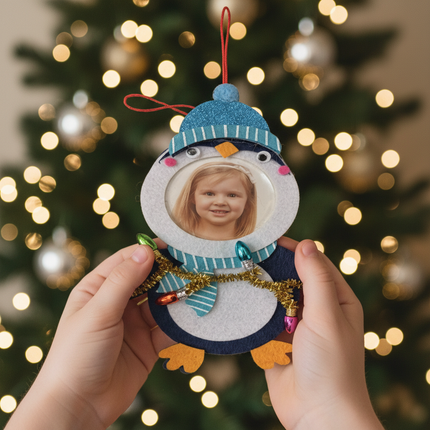 Child holding Studio Decor Felt Penguin Photo Ornament with smiling photo inserted