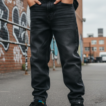 Boy wearing dark wash loose fit skater denim jeans outdoors in an urban setting