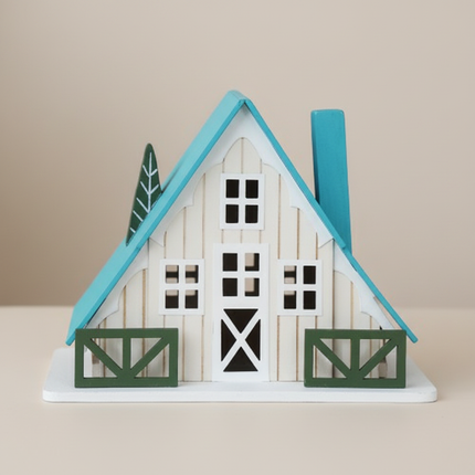 Close-up of white A-frame cottage tabletop decor showing teal roof and window details