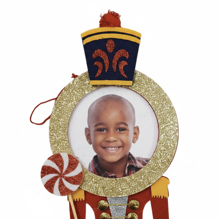 Close up detail of felt nutcracker peppermint ornament navy hat and gold glitter frame