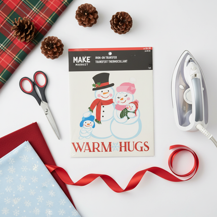 Make Market Christmas iron-on transfer sheet flat lay with holiday craft supplies including scissors, fabric and ribbon
