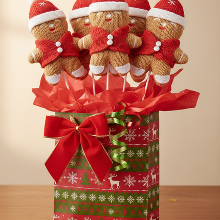 Multiple Ashland 12 inch gingerbread man decorative picks arranged in a Christmas gift bag with tissue paper and holiday ribbon