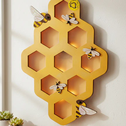 DIY wood honeycomb wall hanging painted in yellow and gold with bee accents as a completed craft project