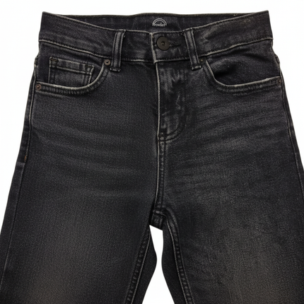 Close-up of dark wash denim fabric texture, waistband, belt loops and stitching detail on boys loose fit skater jeans